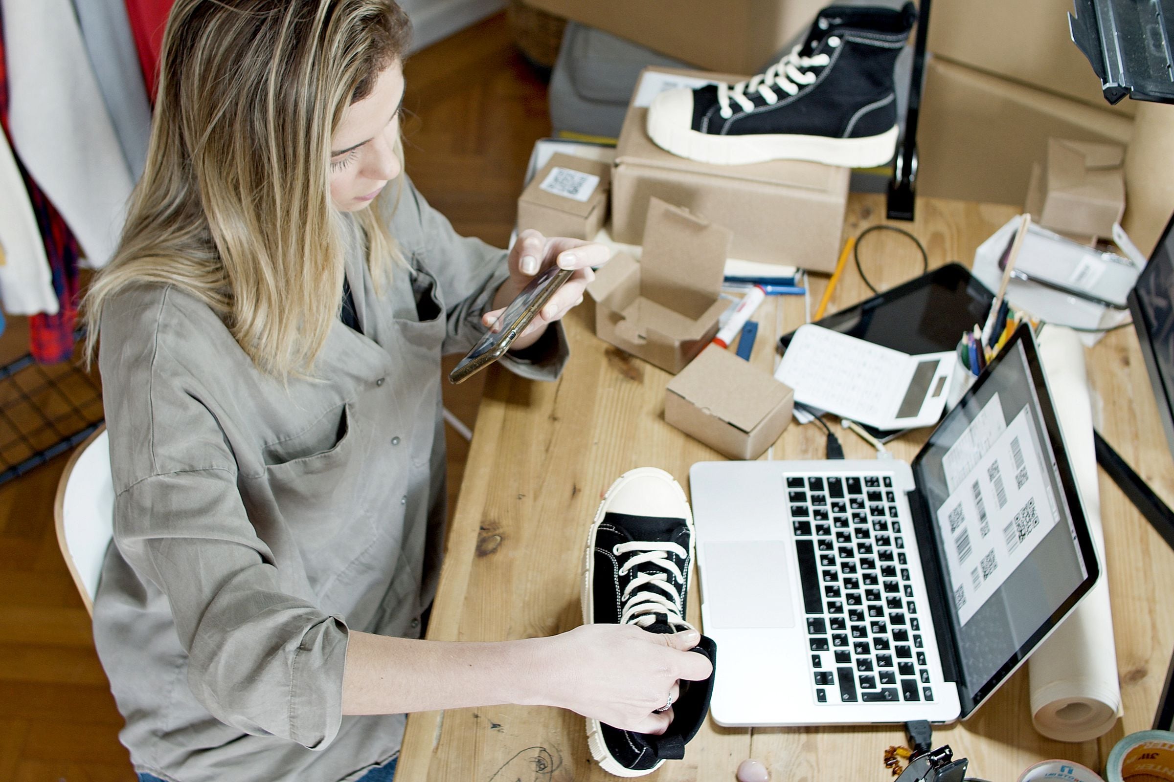 A retailer photographing a product for her online shop beside a laptop