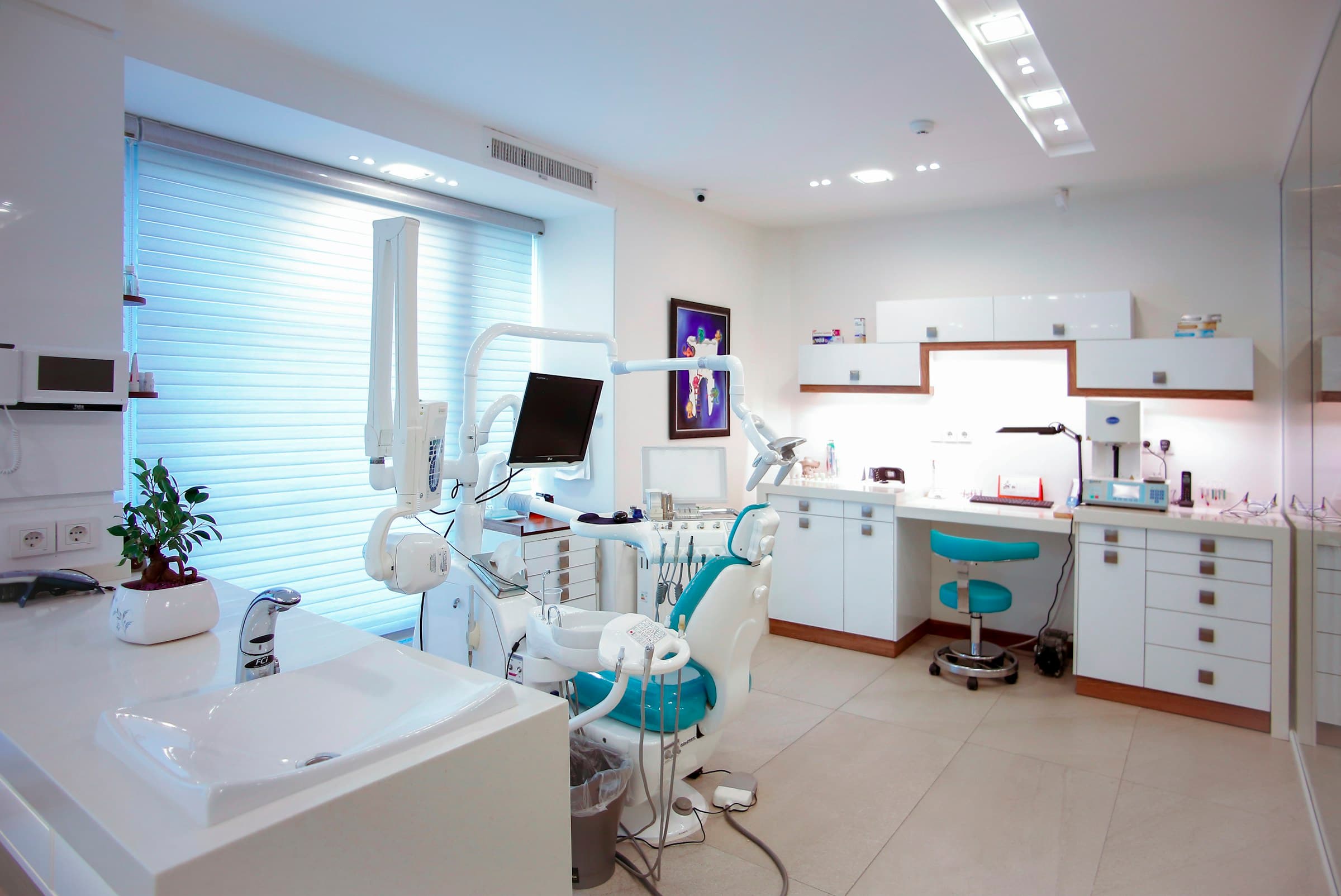 Bright, modern dental clinic with a white and teal treatment chair
